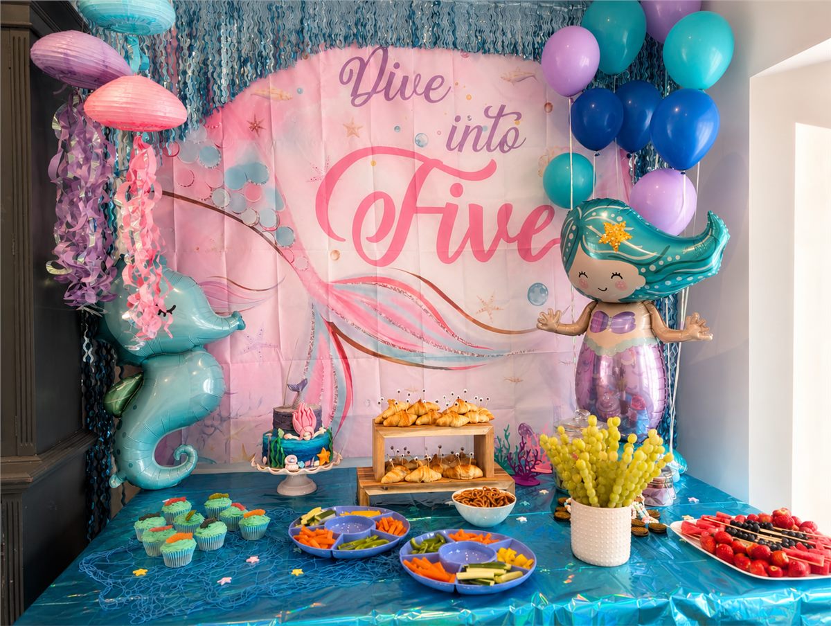 Under-the-sea children's party setup with mermaid decorations, balloons, themed food, and a blue backdrop.