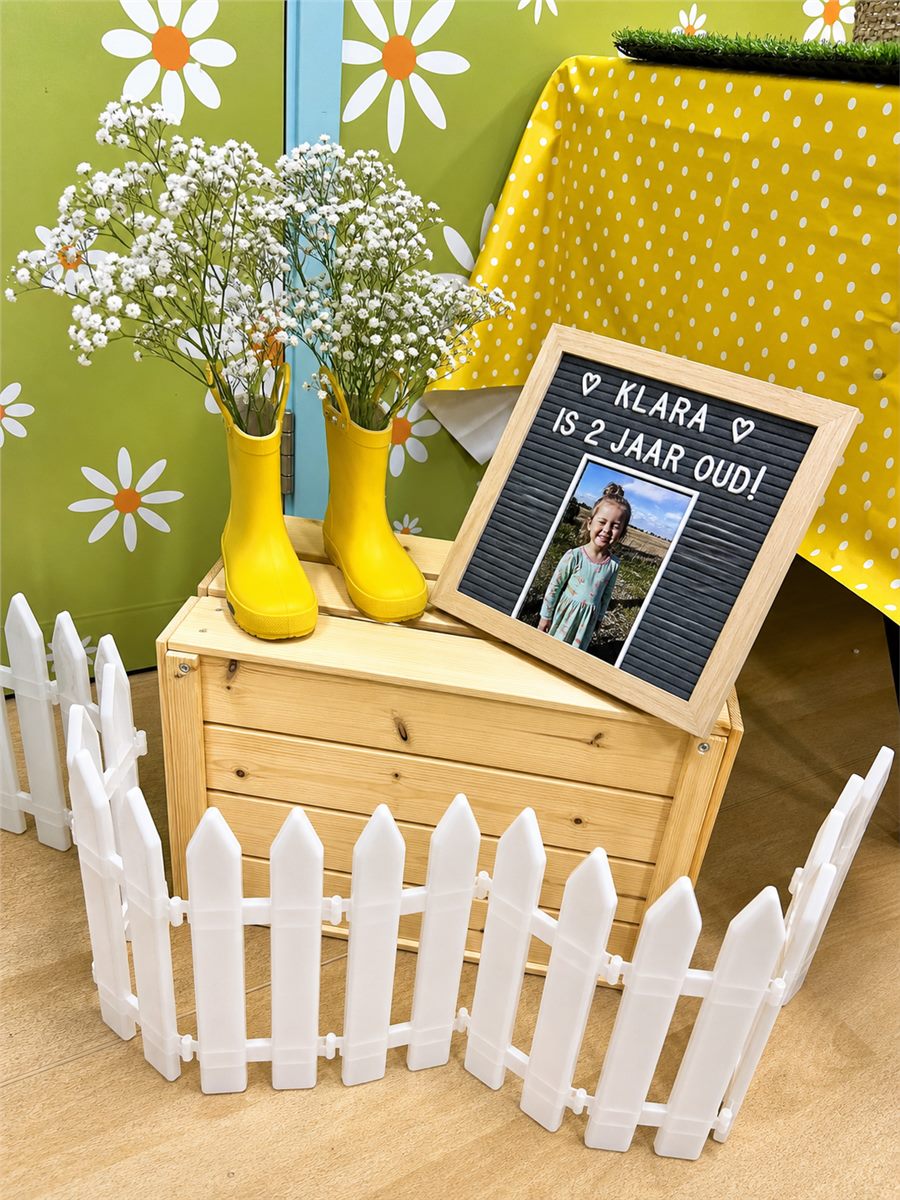 Personalised children's party welcome sign with flowers and a white picket fence.