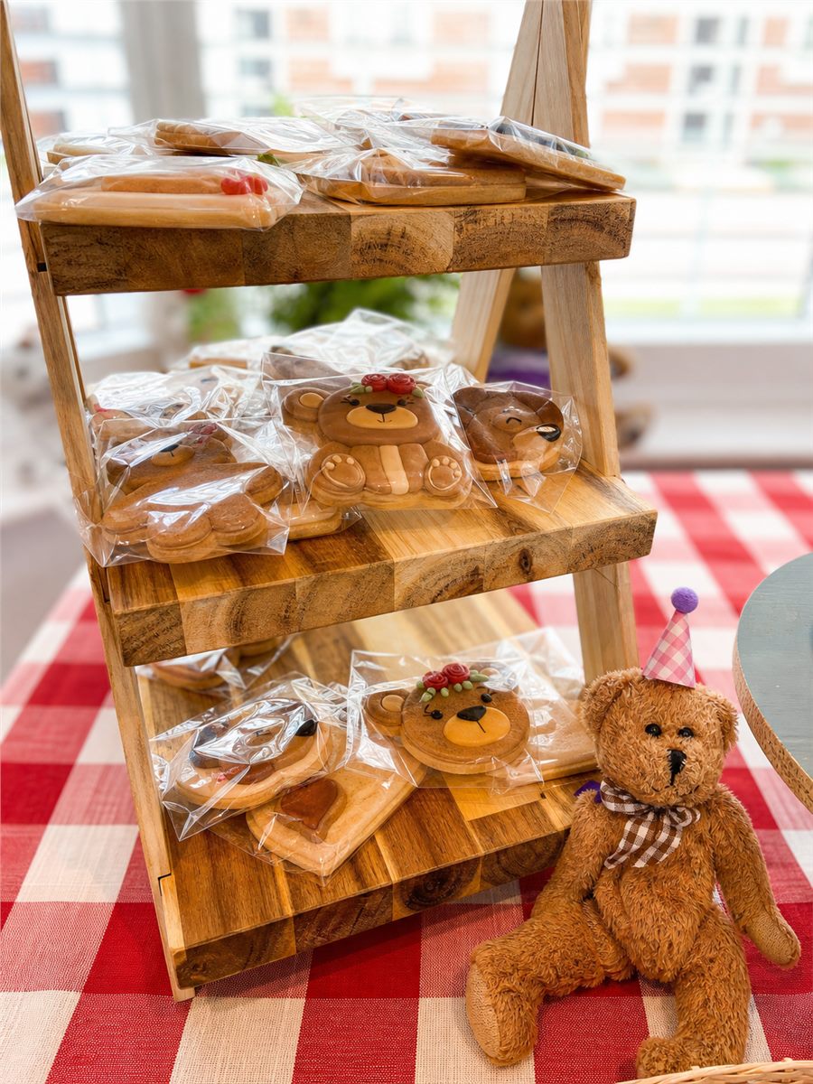 Teddy bear cookies displayed on a wooden shelf.